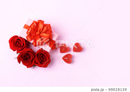 Happy Valentine's Day, Mother's Day and birthday greeting card. Red roses and pink gift box with a red satin ribbon bow and candles in the shape of hearts 99028139