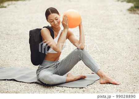 Pretty lady training on a summer beach. Brunette doing yoga. Girl in a sportsuit. Pretty lady training on a summer beach. Brunette doing yoga. Girl in a sportsuit. 99028890