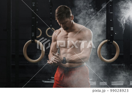 Portrait of muscular crossfit athlete clapping hands and preparing for workout at the gym Portrait of muscular crossfit athlete clapping hands and preparing for workout at the gym 99028923