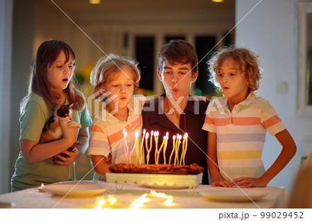 Teenager boy birthday. Siblings blow cake candles 99029452