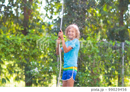 Kids play with water sprinkle hose. Summer garden Kids play with water sprinkle hose. Summer garden 99029456