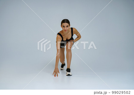 Female athlete runner before start, preparing to run on studio background. Running workout Female athlete runner before start, preparing to run on studio background. Running workout 99029502