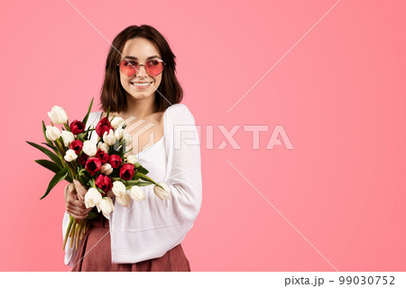 Smiling young european female in glasses with bouquet of flowers, enjoy lifestyle and rejoicing spring holiday 99030752