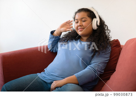 Relaxed hispanic young woman plus size listening to music Relaxed hispanic young woman plus size listening to music 99030873