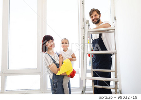 Parents teaches their little daughter household chores, they wash the window in their house 99032719
