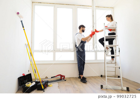 Attractive young couple in rubber gloves with detergent and rag washing windows together. Attractive young couple in rubber gloves with detergent and rag washing windows together. 99032725