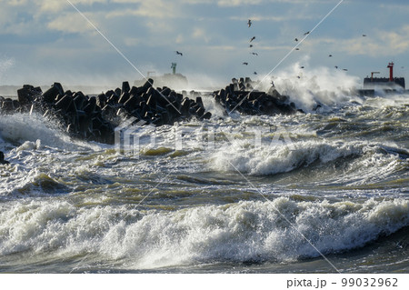 Coastal storm in the Baltic Sea, big waves crash against the harbor breakwater, breaking wave 99032962