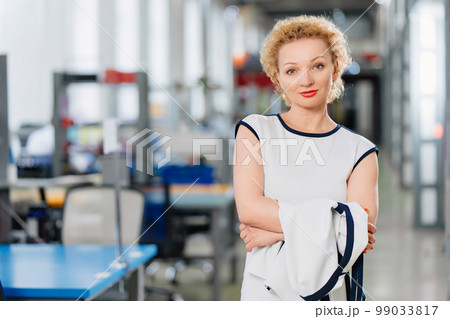 a blonde in a white dress in a big office. the concept of a business portrait.  99033817