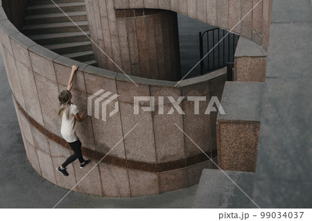 Young sporty woman doing parkour in city 99034037