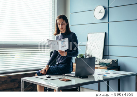 Woman in the office reads a financial report. Woman in the office reads a financial report. 99034959