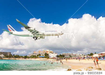 PHILIPSBURG, SINT MAARTEN - DECEMBER 13, 2016: A commercial airplane approaches Princess Juliana airport above onlooking spectators on Maho beach. PHILIPSBURG, SINT MAARTEN - DECEMBER 13, 2016: A commercial airplane approaches Princess Juliana airport above onlooking spectators on Maho beach. 99035694