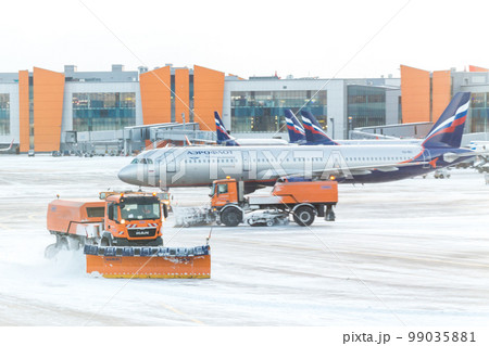 MOSCOW, RUSSIA - DECEMBER 06, 2016 : Snowplow removing snow from runways and roads in airport during snow storm in SHEREMETYEVO airport on December 06.2016 in Moscow. 99035881