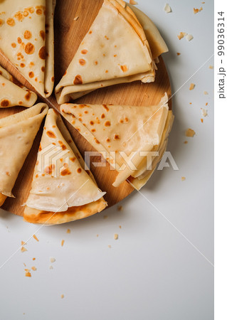 Delicious crepes laid out in triangles in a circle on a wooden board, flat lay 99036314