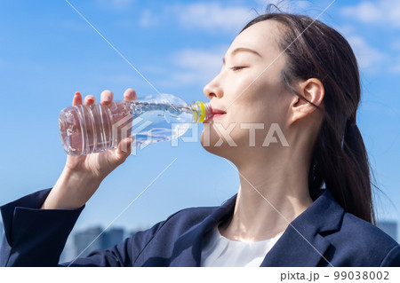 屋外で水分補給をする美容を気遣う若い女性 屋外で水分補給をする美容を気遣う若い女性 99038002