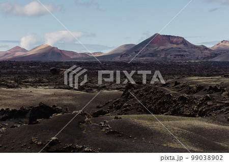 Black volcanic landscape of Timanfaya National Park in Lanzarote. Popular touristic attraction in Lanzarote island, Canary Islands, Spain 99038902