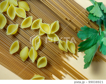 Spaghetti of two types on the table. shells and buckwheat pasta. Italian food. Long pasta. Cooking food. Spaghetti of two types on the table. shells and buckwheat pasta. Italian food. Long pasta. Cooking food. 99038921