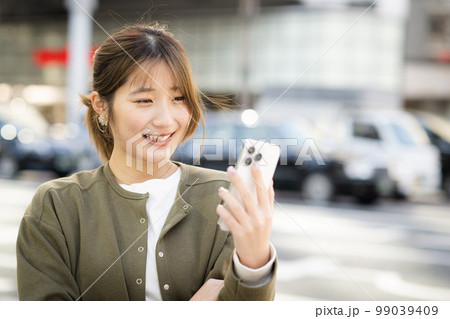 スマホを見る笑顔の若い女性・ビジネスウーマン スマホを見る笑顔の若い女性・ビジネスウーマン 99039409
