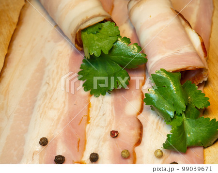 Curvy cut folded into rolls. Pork on a kitchen board with parsley.  Pork belly appetizer. 99039671