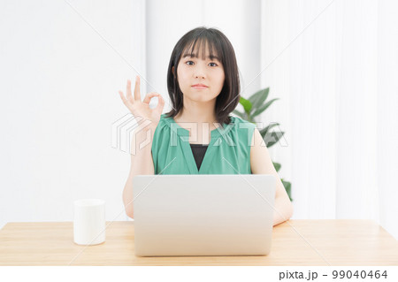 PCの前でOKのサインをする若い女性 PCの前でOKのサインをする若い女性 99040464