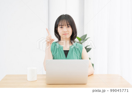 パソコンを使いながらポイントを示す若い女性 パソコンを使いながらポイントを示す若い女性 99045771