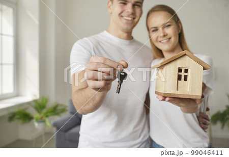 Small house and key in hands of joyful couple who are happy about successful purchase of real estate 99046411