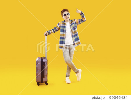 Excited tourist boy traveling with luggage on summer vacation 99046484