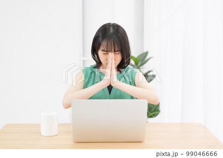 PCの前で手を合わせて祈っている若い女性 PCの前で手を合わせて祈っている若い女性 99046666