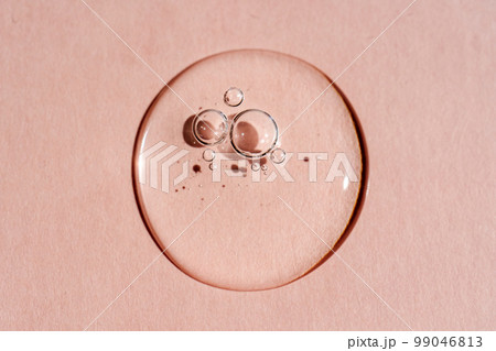 A drop of transparent cosmetic gel on a pink background. 99046813