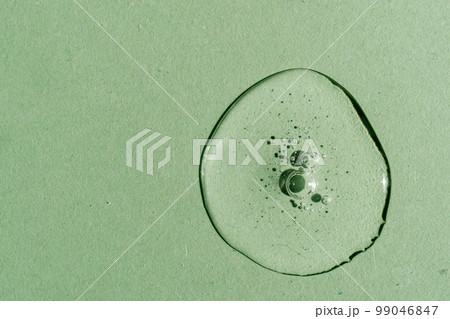 A drop of transparent cosmetic gel on a green background. A drop of transparent cosmetic gel on a green background. 99046847
