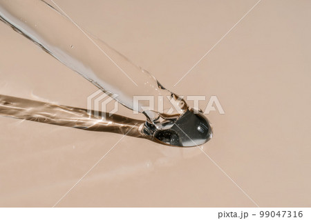 A drop of cosmetic oil falls from the pipette 99047316