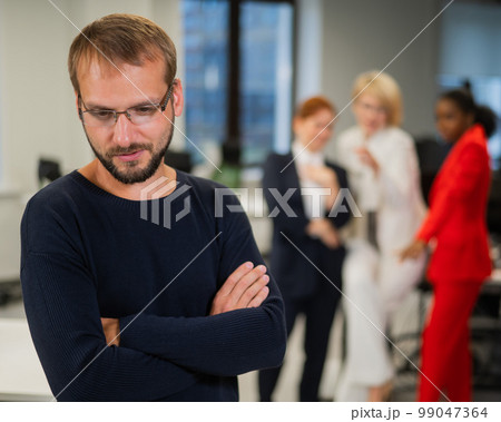 A middle-aged man is upset because of the ridicule of his female colleagues. Discrimination against men in the office.  99047364