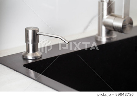 Dispenser in the kitchen built into the sink for dish detergent. Copy space for text, decor 99048756