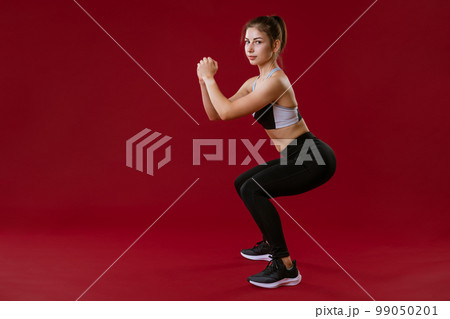 young woman is engaged in fitness on a red background 99050201