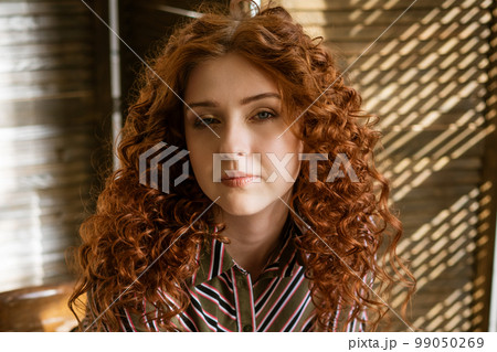 Portrait of a young red-haired woman with sad eyes Portrait of a young red-haired woman with sad eyes 99050269