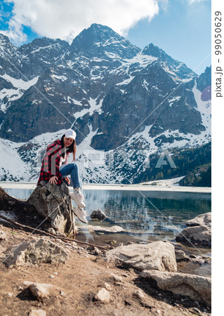 A woman is sitting on the shore of a lake. Morskie Oko, Tatras mountains. 99050629