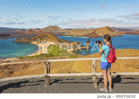 Galapagos islands tourist hiking taking photo on Bartolome Island hike. Woman photographer on wildlife excursion cruise, Islas Galapagos archipelago. Sullivan bay, east coast of Santiago island 99050830