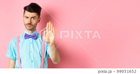 Serious-looking man prohibit something bad, stretch out hand to stop you, forbid action, saying no and looking strict, standing over pink background Serious-looking man prohibit something bad, stretch out hand to stop you, forbid action, saying no and looking strict, standing over pink background 99051652