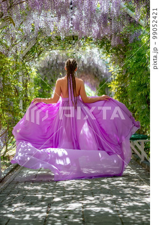 Woman wisteria lilac dress. Thoughtful happy mature woman in pur 99052421