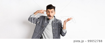 Are you crazy. Angry man scolding person for stupid actions, pointing at head temple and raising hand confused, complaining while standing on white background 99052788