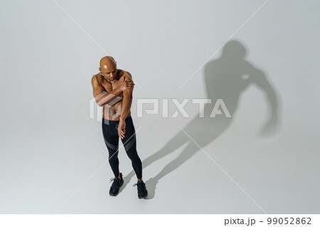 Top view of sportsman with naked torso is warming up on white studio background before workout Top view of sportsman with naked torso is warming up on white studio background before workout 99052862