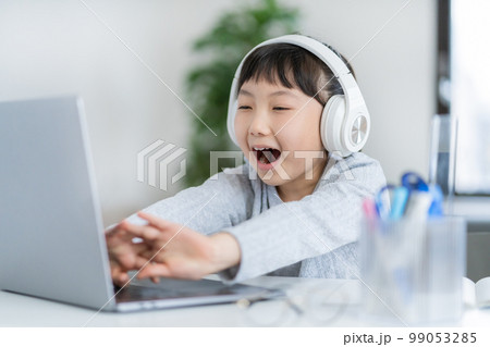 ヘッドフォンをして背伸びをする小学生の女の子 99053285