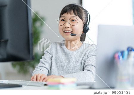 ヘッドセットをしてパソコンを操作する小学生の女の子 ヘッドセットをしてパソコンを操作する小学生の女の子 99053455