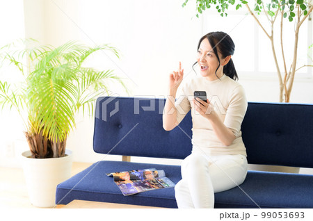 スマホを片手に考え中のミドル女性 スマホを片手に考え中のミドル女性 99053693