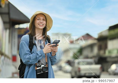 Caucasian female traveler using smart phone and waiting for cab for transporting. Tourism and transportation concept 99057907
