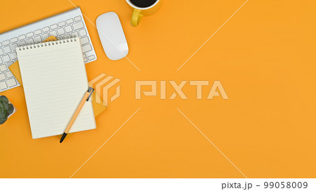 Top view of notepad, keyboard, mouse and coffee cup on yellow background. Copy space for your text Top view of notepad, keyboard, mouse and coffee cup on yellow background. Copy space for your text 99058009