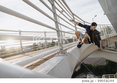 Parkour athlete hanging on the bridge and ready for dangerous jump 99058244