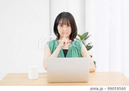 PCを使いながら口を指で押さえる若い女性 PCを使いながら口を指で押さえる若い女性 99059560