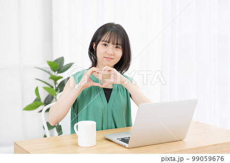 手でハートの形を作って見せる若い女性 手でハートの形を作って見せる若い女性 99059676