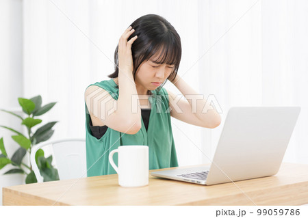 パソコンの前で騒音に困っている若い女性 パソコンの前で騒音に困っている若い女性 99059786