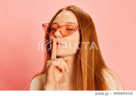 Closeup young beautiful redhaired girl with long hair isolated over light pink background. Concept of positive emotions, happy mood, fashion, youth Closeup young beautiful redhaired girl with long hair isolated over light pink background. Concept of positive emotions, happy mood, fashion, youth 99060458
